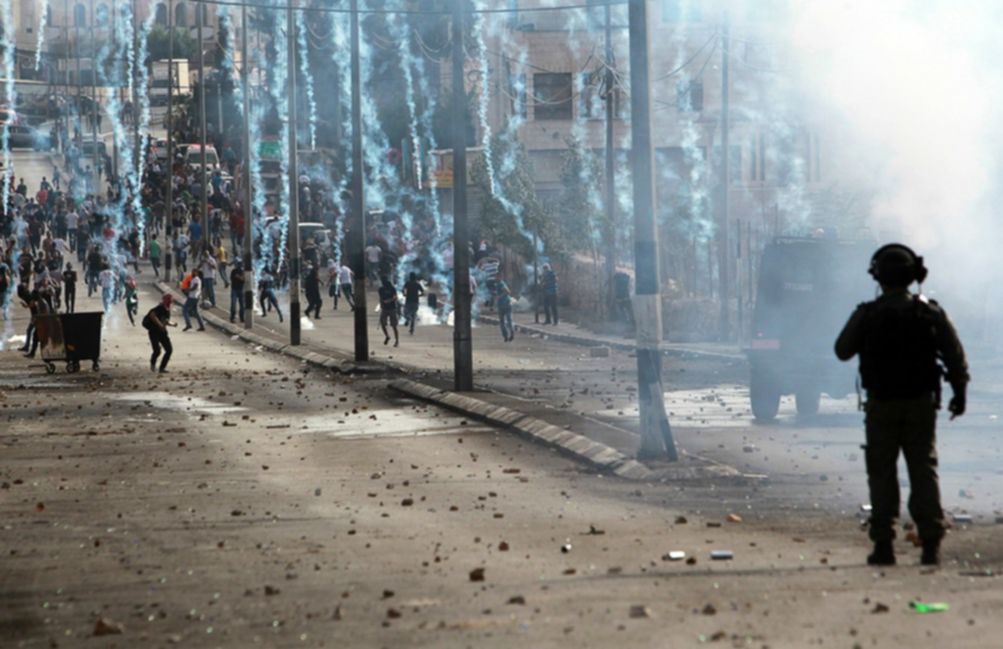 A member of Israeli security forces stands guard as tear gas rains down on in front of Palestinian stone throwers in the West Bank city of BethlehemMusa al Shaer AFP