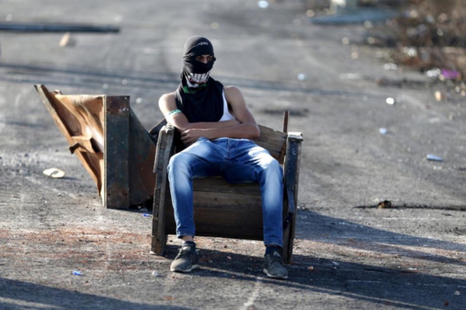 A protester sits on a chair during clashes with Israeli troops near the Jewish settlement of Bet El October 11 2015. Mohamad Torokman Reuters